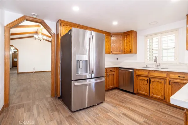 a kitchen with stainless steel appliances granite countertop a refrigerator a sink dishwasher and wooden cabinets with wooden floor