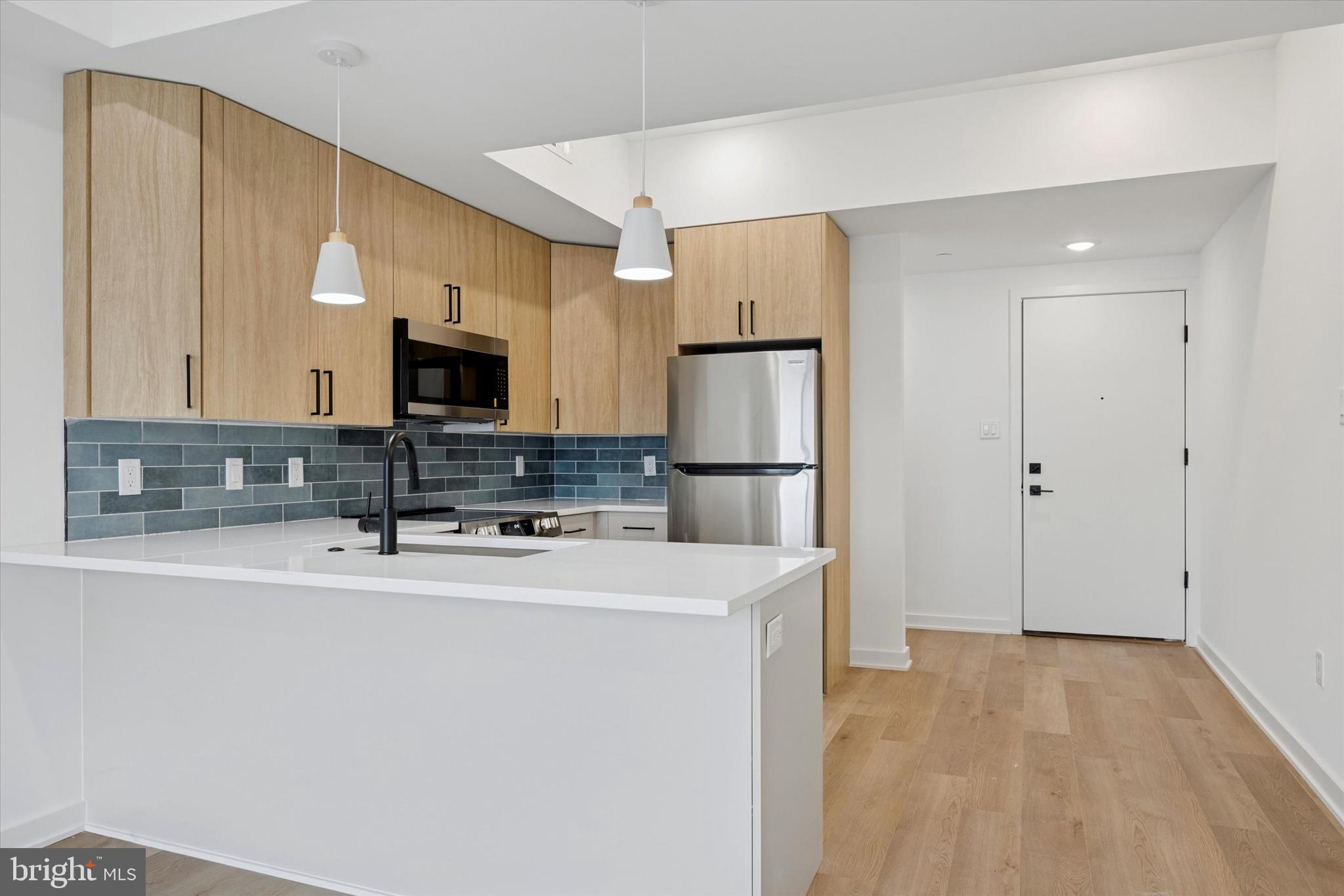 2020 Frankford Avenue, Unit 201 Philadelphia, PA 19125 - Photo 6 of 14 a kitchen with kitchen island a white counter top space cabinets and stainless steel appliances