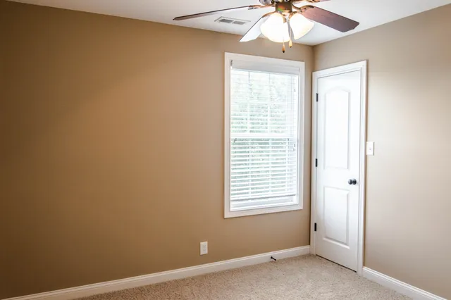 an empty room with a window and a chandelier fan