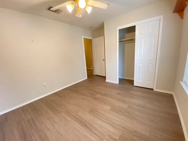 a view of an empty room with wooden floor and a window