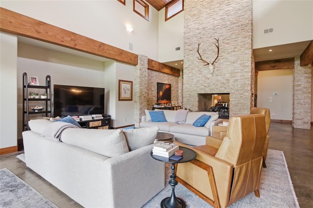 1138 Bancroft Road Keller, TX 76248 - Photo 11 of 39 Spacious living area featuring a floor-to-ceiling stone fireplace, high vaulted ceilings, exposed wood beams, polished concrete flooring, and recessed lighting