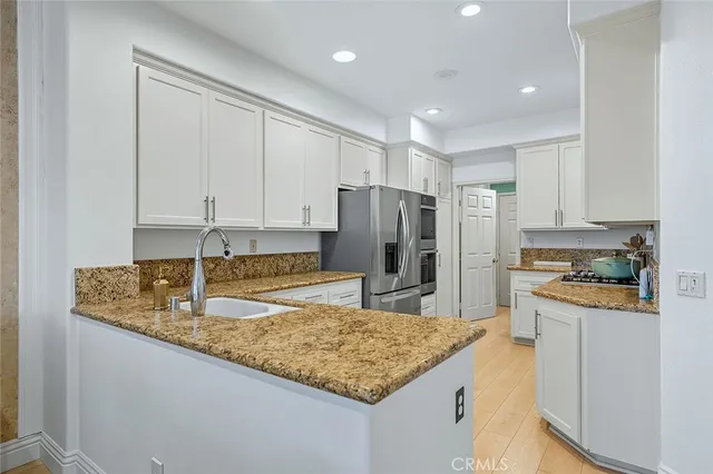 a kitchen with stainless steel appliances granite countertop a refrigerator and a stove top oven