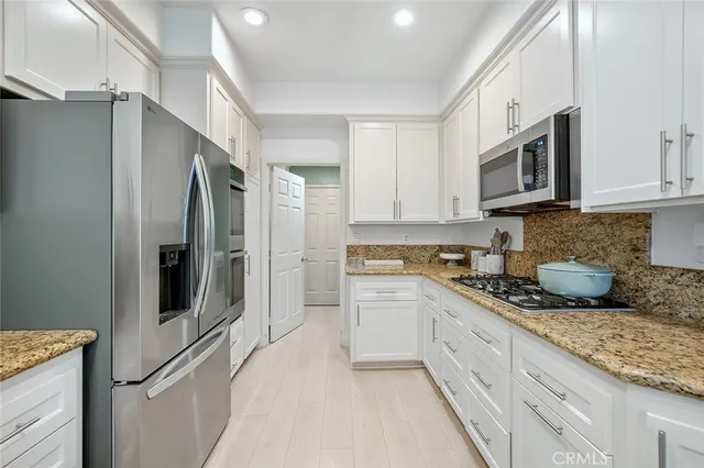 a kitchen with stainless steel appliances granite countertop a sink a stove a refrigerator and cabinets