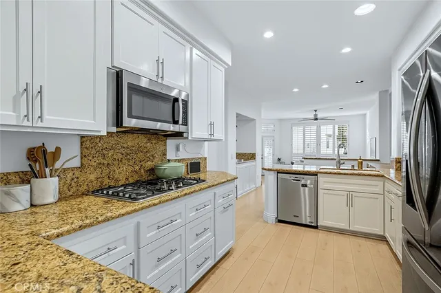 a kitchen with stainless steel appliances granite countertop a stove a sink a dining table and chairs