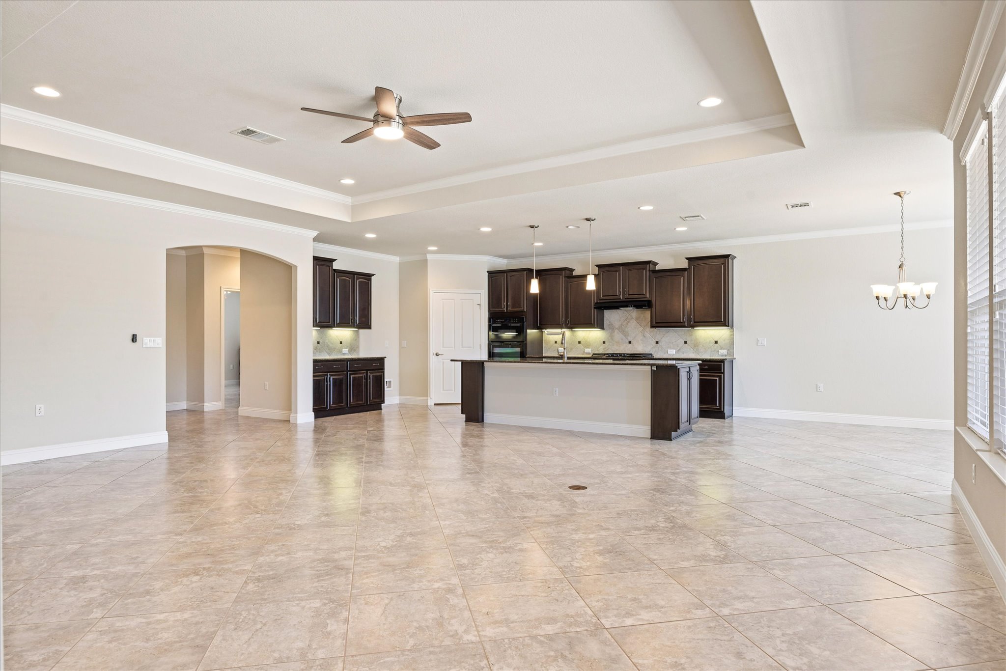 Polished tile flooring flows seamlessly through this open-concept layout beneath elegant tray ceilings.