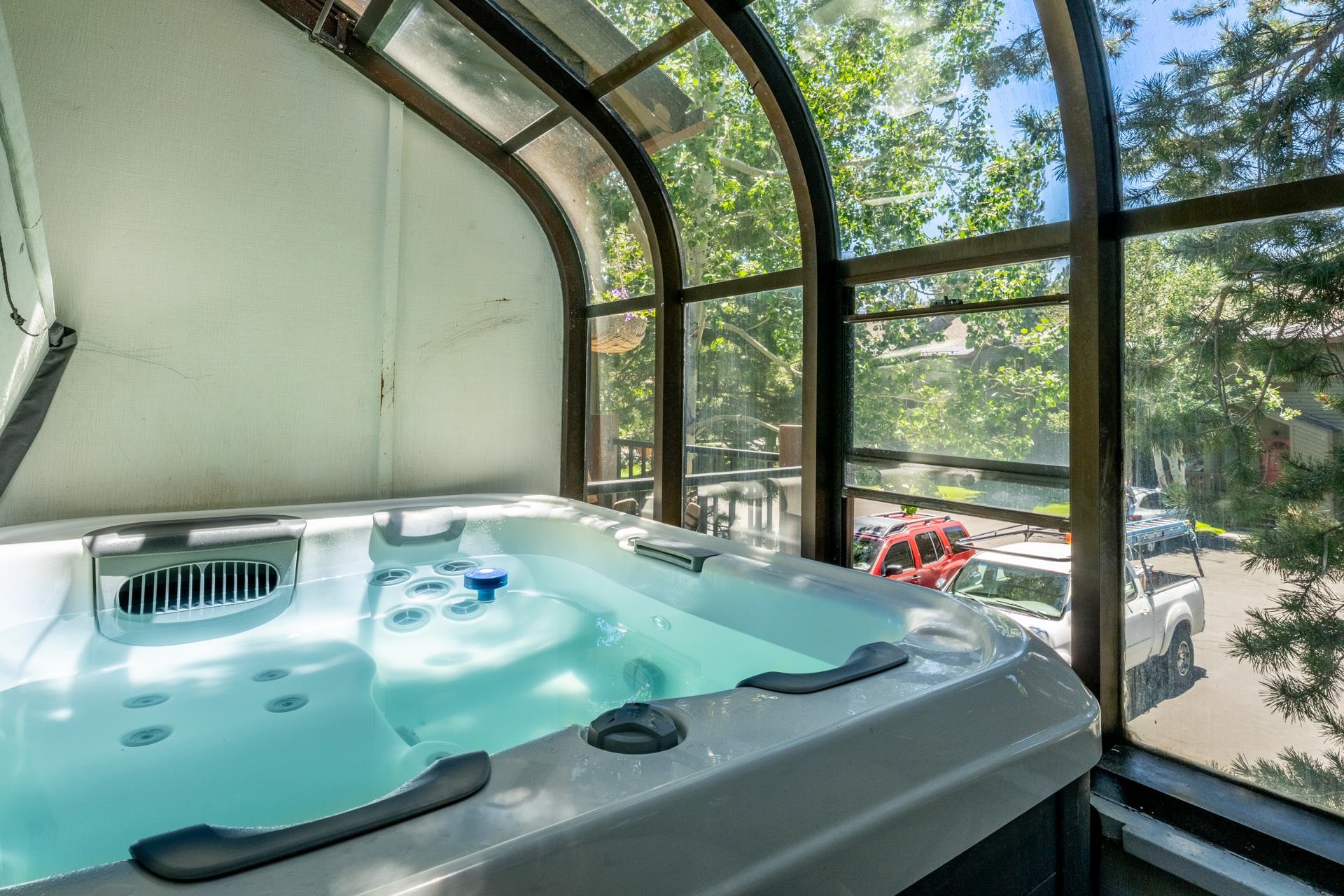 384 Joaquin Road, Unit 36 Mammoth Lakes, CA 93546 - Photo 21 of 36 Enclosed hot tub area featuring expansive arched windows, a white soaking tub with multiple jets, and a partial view of mature trees