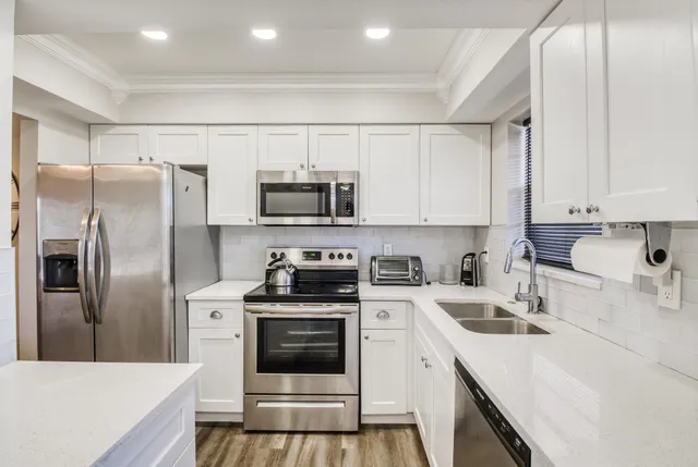 a kitchen with stainless steel appliances a sink stove refrigerator and cabinets