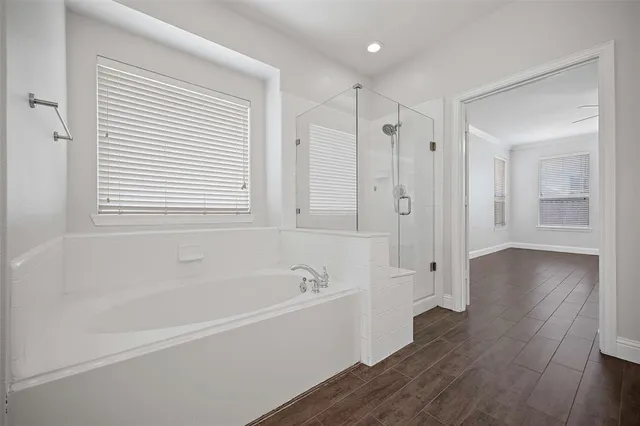 a white bath tub sitting in a spacious bathroom next to a window