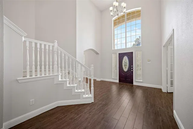 an empty room with wooden floor staircase and windows