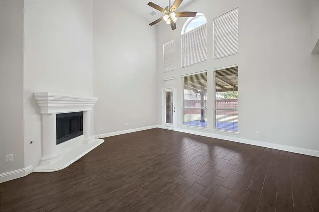 an empty room with wooden floor fireplace and windows