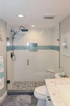 a bathroom with a granite countertop sink a toilet and shower