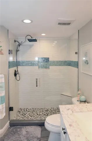 a bathroom with a granite countertop sink a toilet and shower