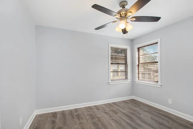 an empty room with window and ceiling fan