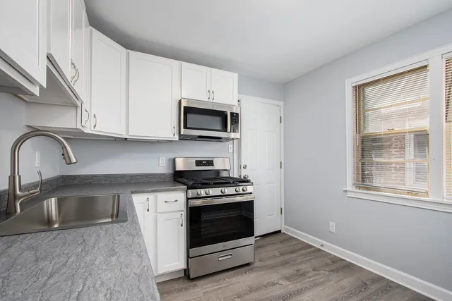 a kitchen with granite countertop a stove a sink and a microwave