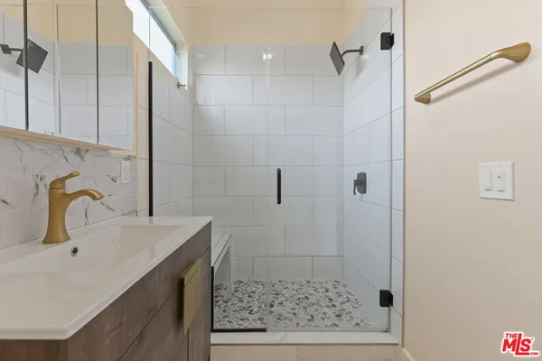 a bathroom with a sink shower and a mirror