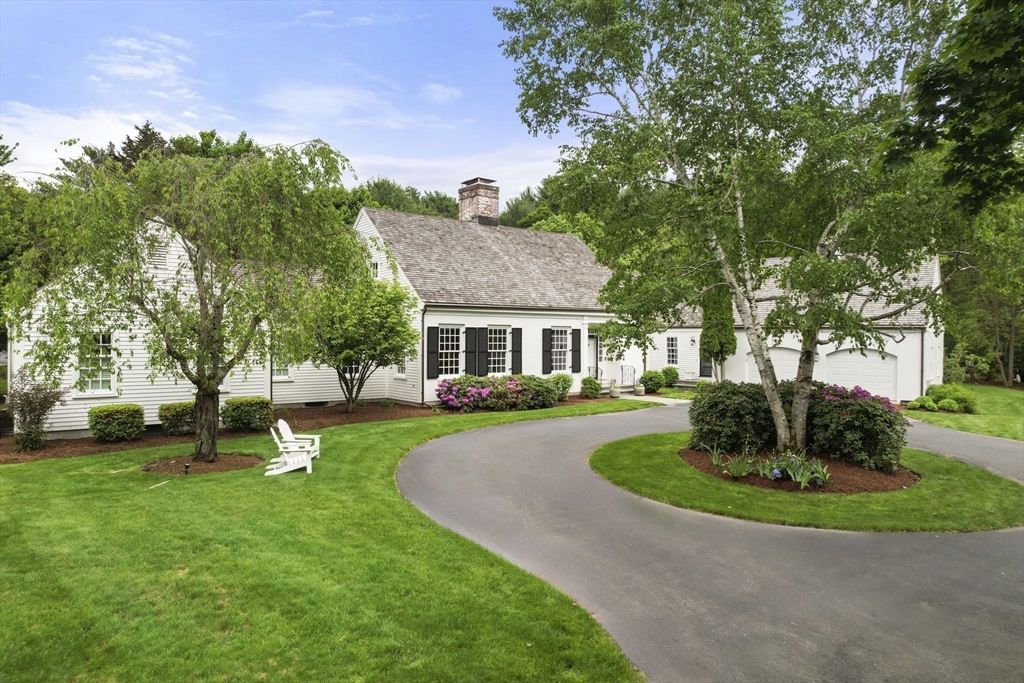 a front view of a house with garden and trees