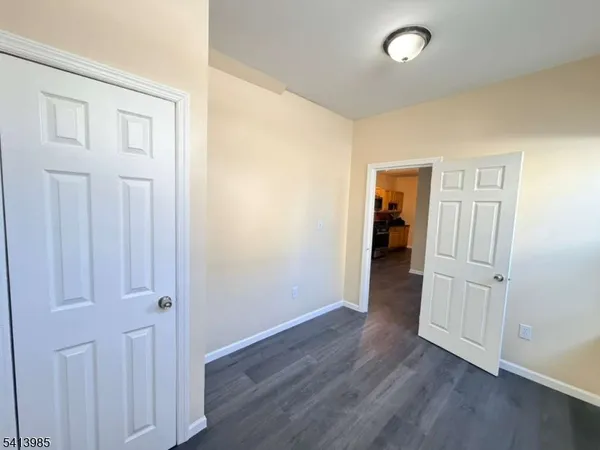 an empty room with wooden floor & closet area