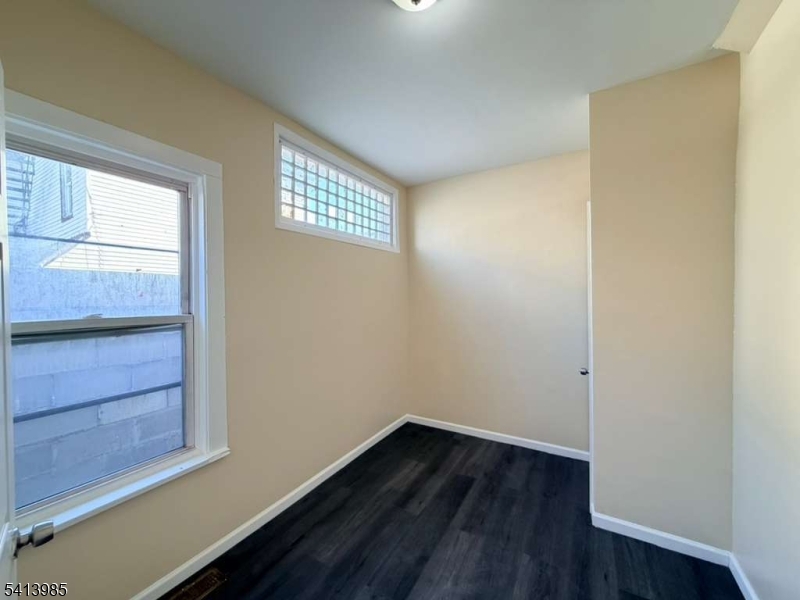 113 Delavan Avenue Newark, NJ 07104 - Photo 2 of 6 a view of an empty room with wooden floor and a window