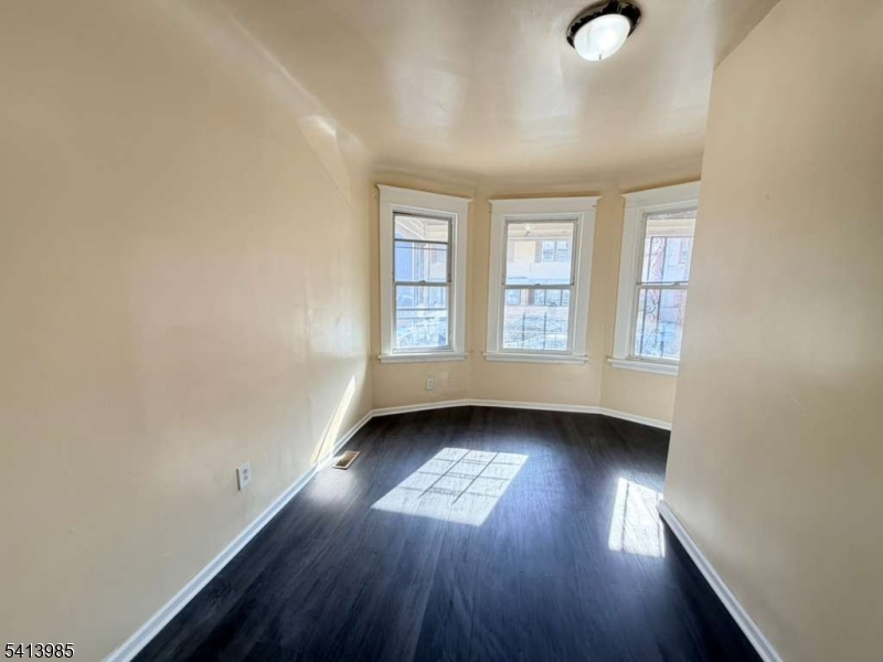 113 Delavan Avenue Newark, NJ 07104 - Photo 4 of 6 an empty room with wooden floor and windows