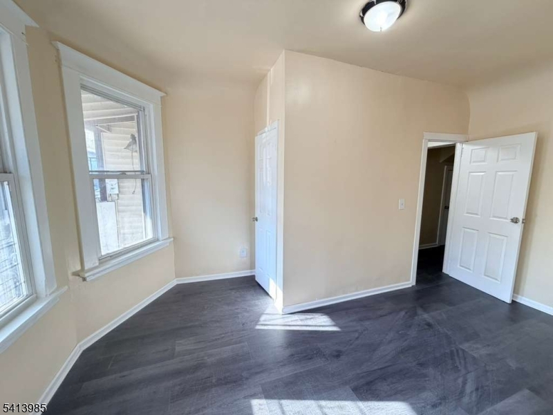 113 Delavan Avenue Newark, NJ 07104 - Photo 5 of 6 an empty room with wooden floor and windows