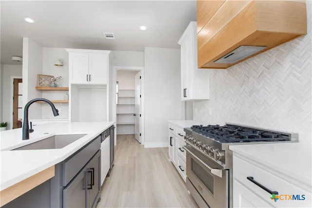 a kitchen with kitchen island stainless steel appliances a sink stove and cabinets