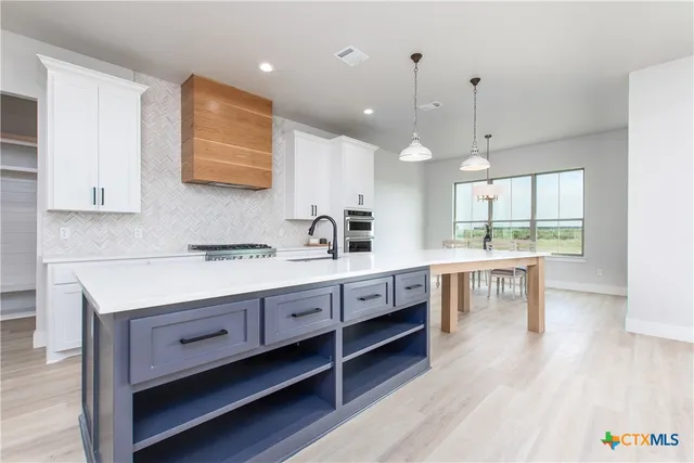 a large kitchen with kitchen island a sink stainless steel appliances and cabinets