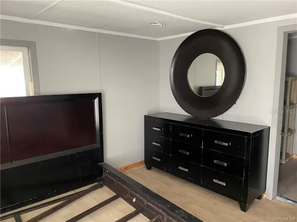 a room with a mirror on the dresser and a window