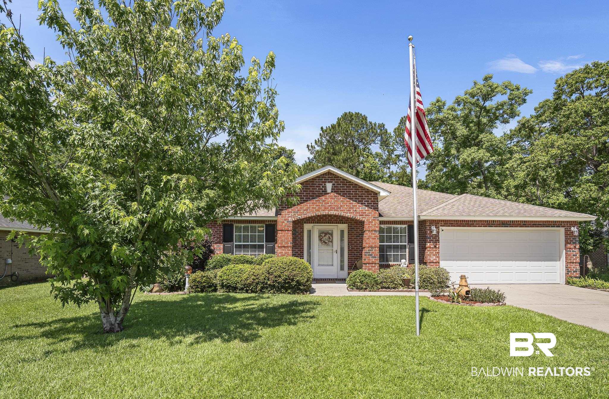 View of front facade with brick siding, concrete driveway, a garage, and a front lawn