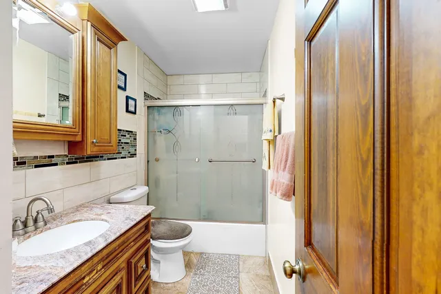 a bathroom with a granite countertop sink toilet and shower