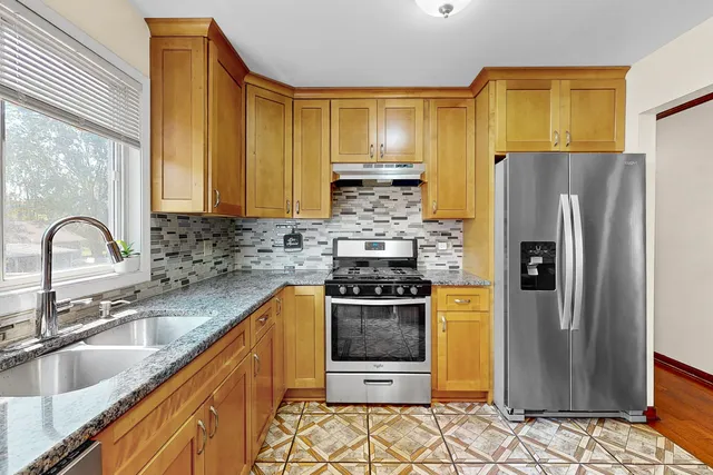 a kitchen with granite countertop a refrigerator and a sink