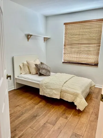 a bedroom with a bed wooden floor and window