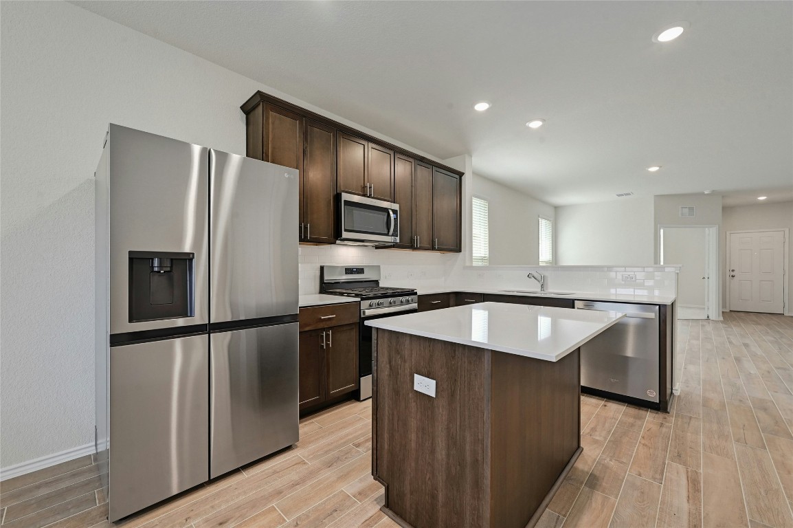 529 Tree Nut Loop Buda, TX 78610 - Photo 12 of 37 a kitchen with stainless steel appliances granite countertop a refrigerator a sink dishwasher a oven with wooden cabinets and wooden floor