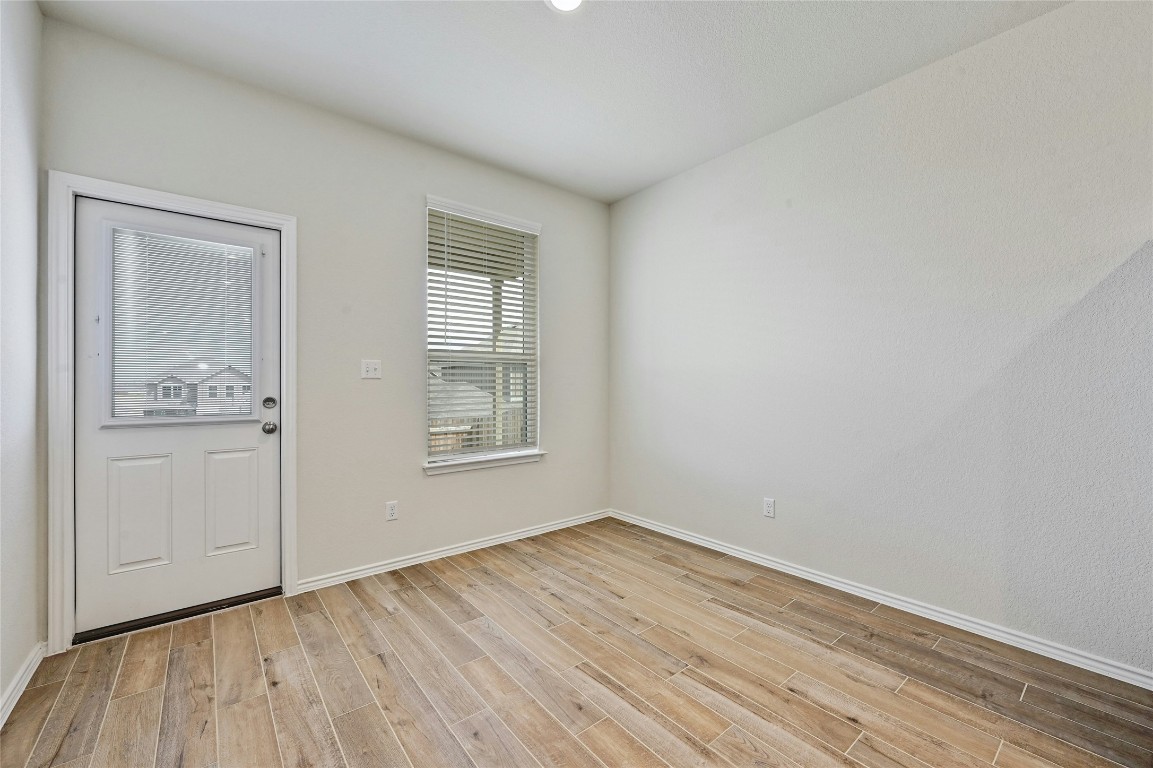 529 Tree Nut Loop Buda, TX 78610 - Photo 13 of 37 an empty room with wooden floor and windows