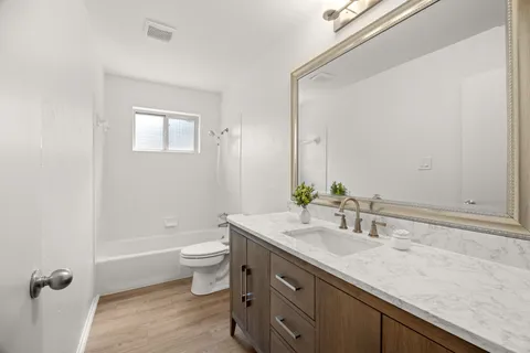 a bathroom with a granite countertop sink a toilet and a mirror