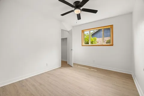 an empty room with wooden floor and ceiling fan
