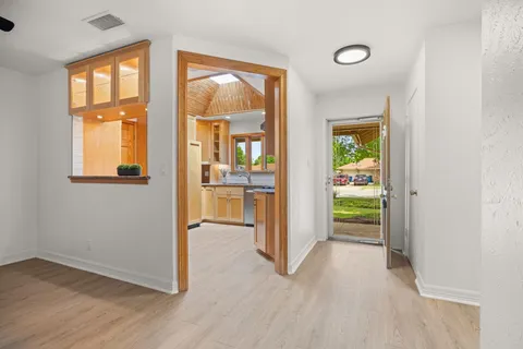 a view of a hallway with wooden floor and a kitchen
