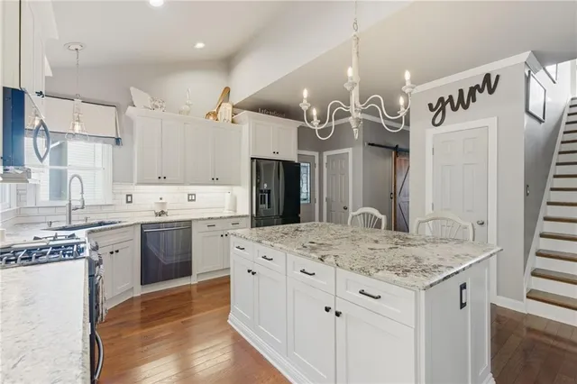 a kitchen with stainless steel appliances kitchen island granite countertop a sink stove and refrigerator