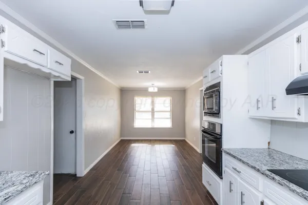 a kitchen with granite countertop a stove a sink and a refrigerator