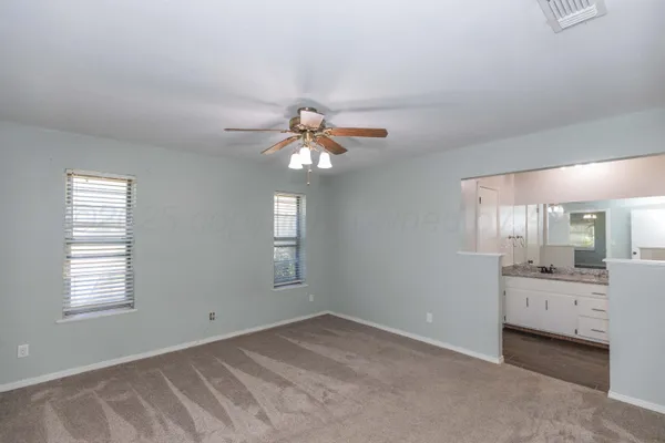 a view of a livingroom with a chandelier fan and windows