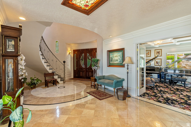 4093 North Imperial Way Provo, UT 84604 - Photo 12 of 96 Grand foyer featuring a curved staircase with wrought iron railing, double-door entry, a patterned tile floor, and a stained-glass ceiling insert