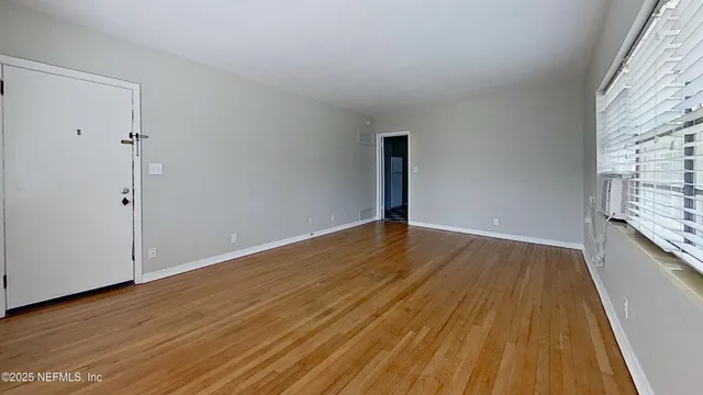 a view of an empty room with wooden floor