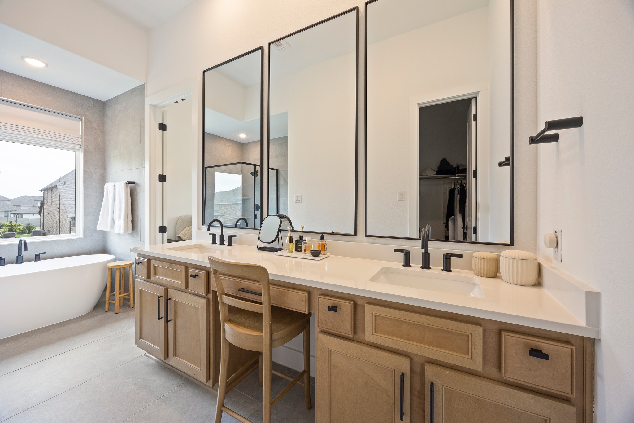 1204 Addison Lane Georgetown, TX 78628 - Photo 14 of 35 Indulge in a spa-like experience at home. This luxurious bathroom has an oversized double vanity with a dedicated makeup station, sleek matte black fixtures, and minimalist mirrors.