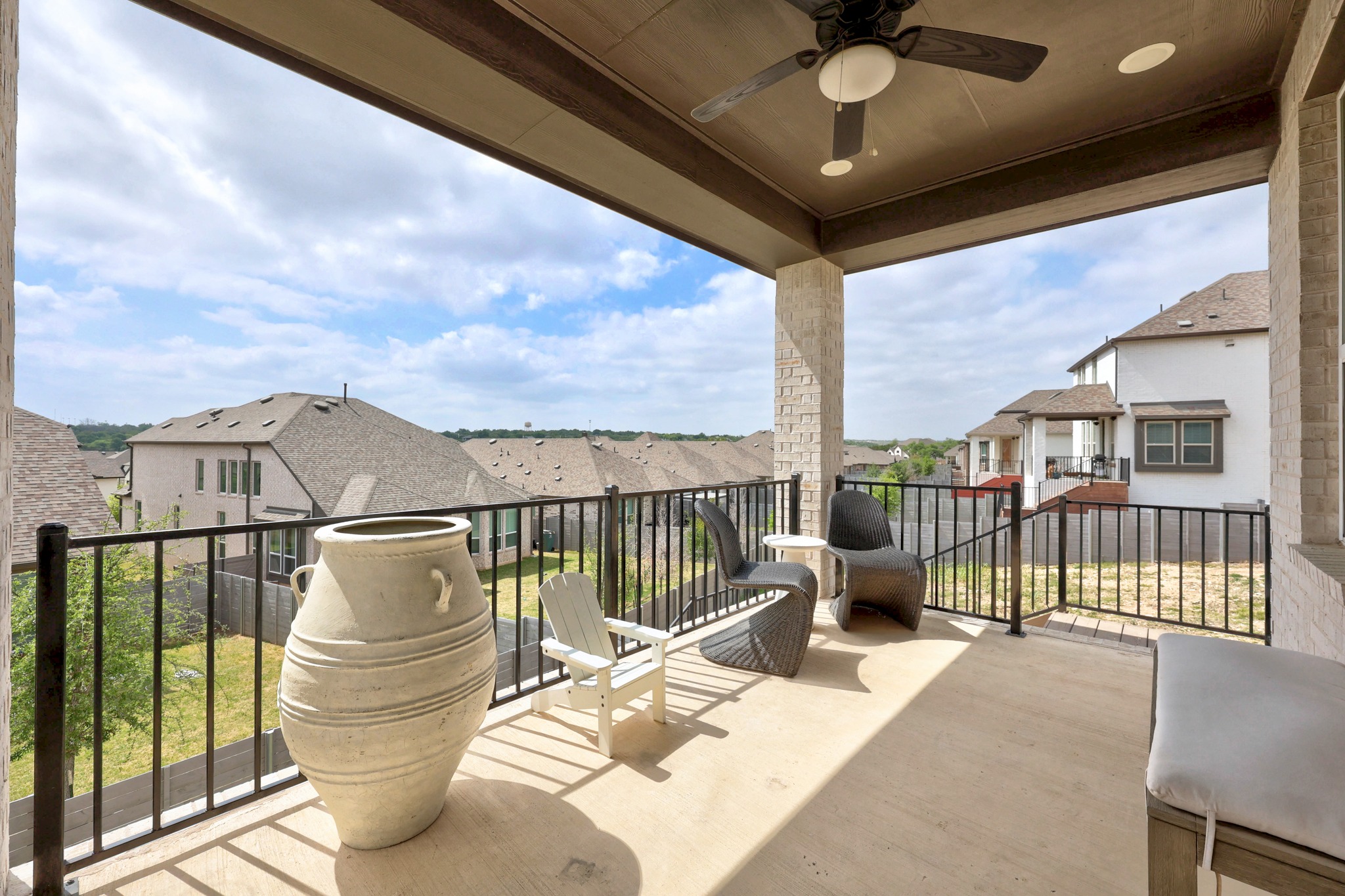 1204 Addison Lane Georgetown, TX 78628 - Photo 22 of 35 Enjoy the gentle Texas breeze from this expansive covered balcony. The space features a warm wood-plank ceiling with a built-in fan and recessed lighting, offering a panoramic view of the surrounding hills.