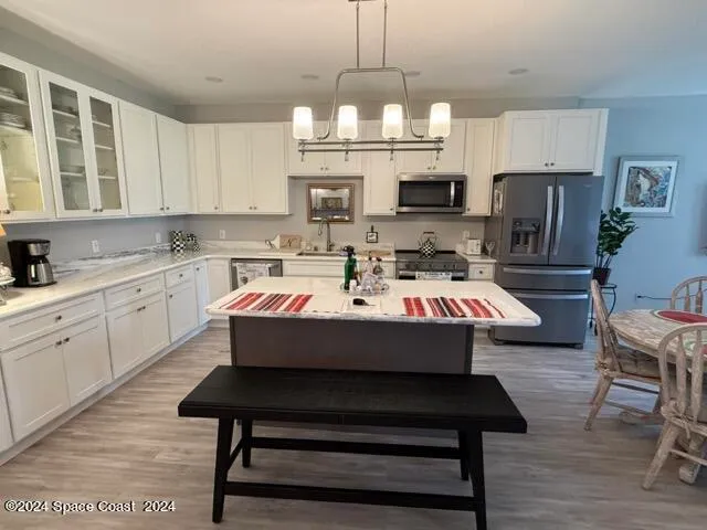 a room with kitchen island a dining table wooden floor and a chandelier