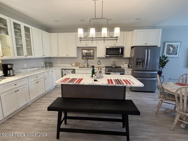 917 Ocaso Lane Rockledge, FL 32955 - Photo 3 of 22 a room with kitchen island a dining table wooden floor and a chandelier