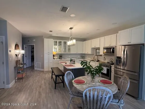 a kitchen with refrigerator a sink and chairs