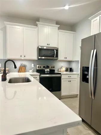 a kitchen with stainless steel appliances a refrigerator sink and white cabinets