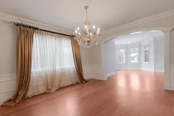 an empty room with wooden floor staircase and windows