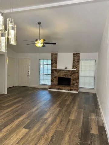 a view of an empty room with wooden floor fireplace and a window
