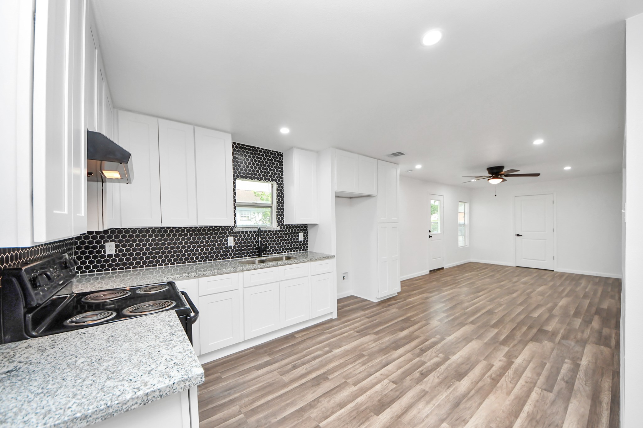 207 East Defee Avenue Baytown, TX 77520 - Photo 14 of 36 a large white kitchen with a sink and a stove top oven with wooden floor